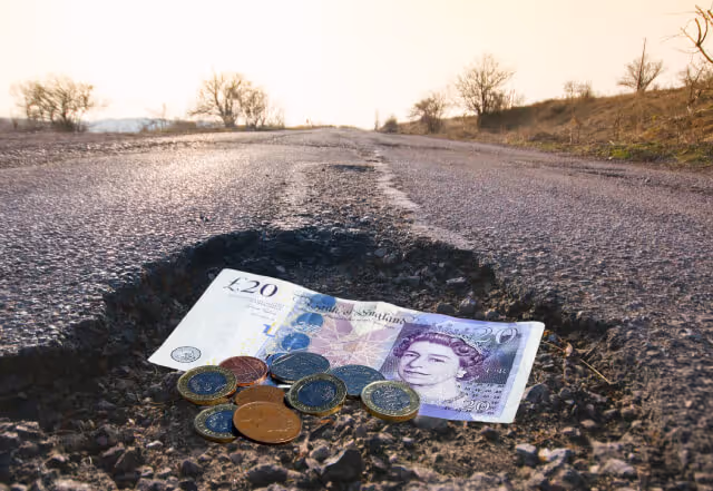 A pothole filled with UK British pounds and sterlings