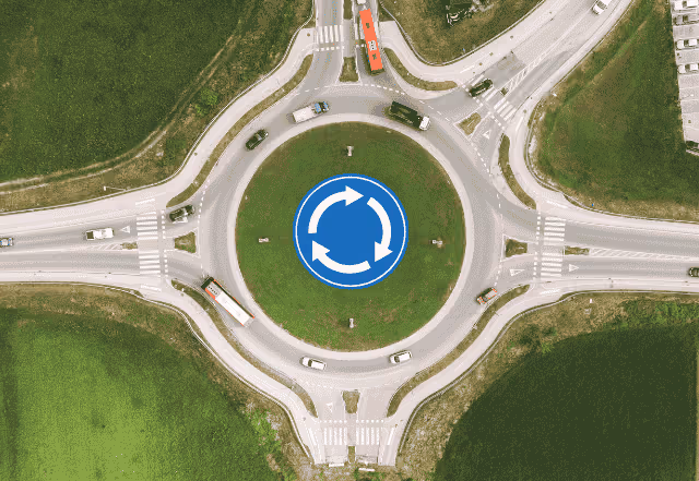 A picture of a roundabout at night with a sign